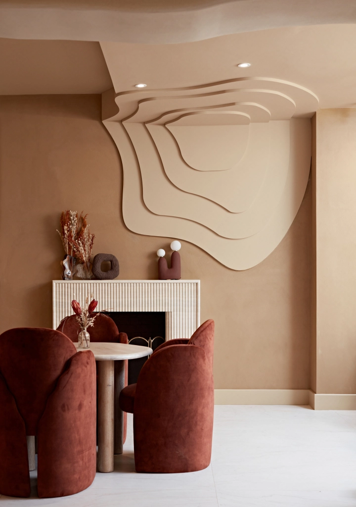 Private dining corner at Curve Club with rust velvet chairs, round table and sculptural wall art
