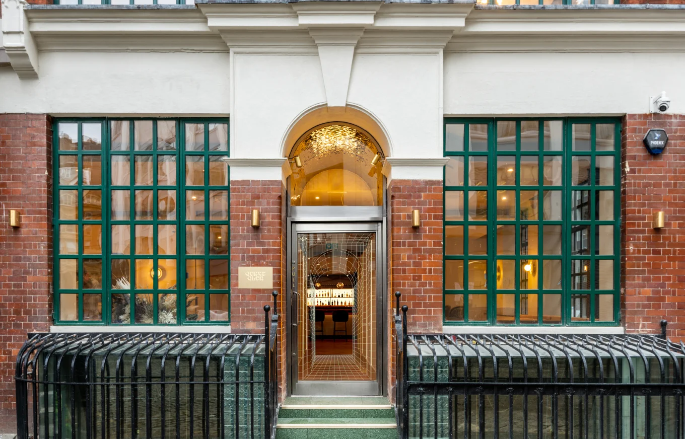 Exterior entrance to Curve Club with green framed windows and arched doorway